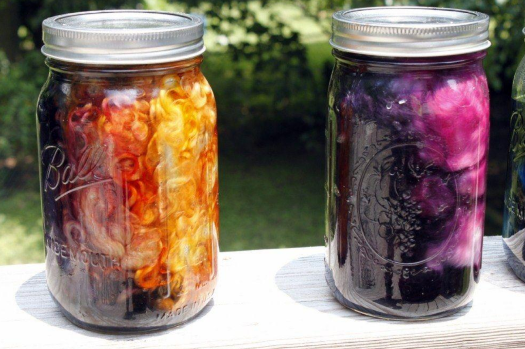 Photo of assorted natural dyes in a large glass  jars on deck.