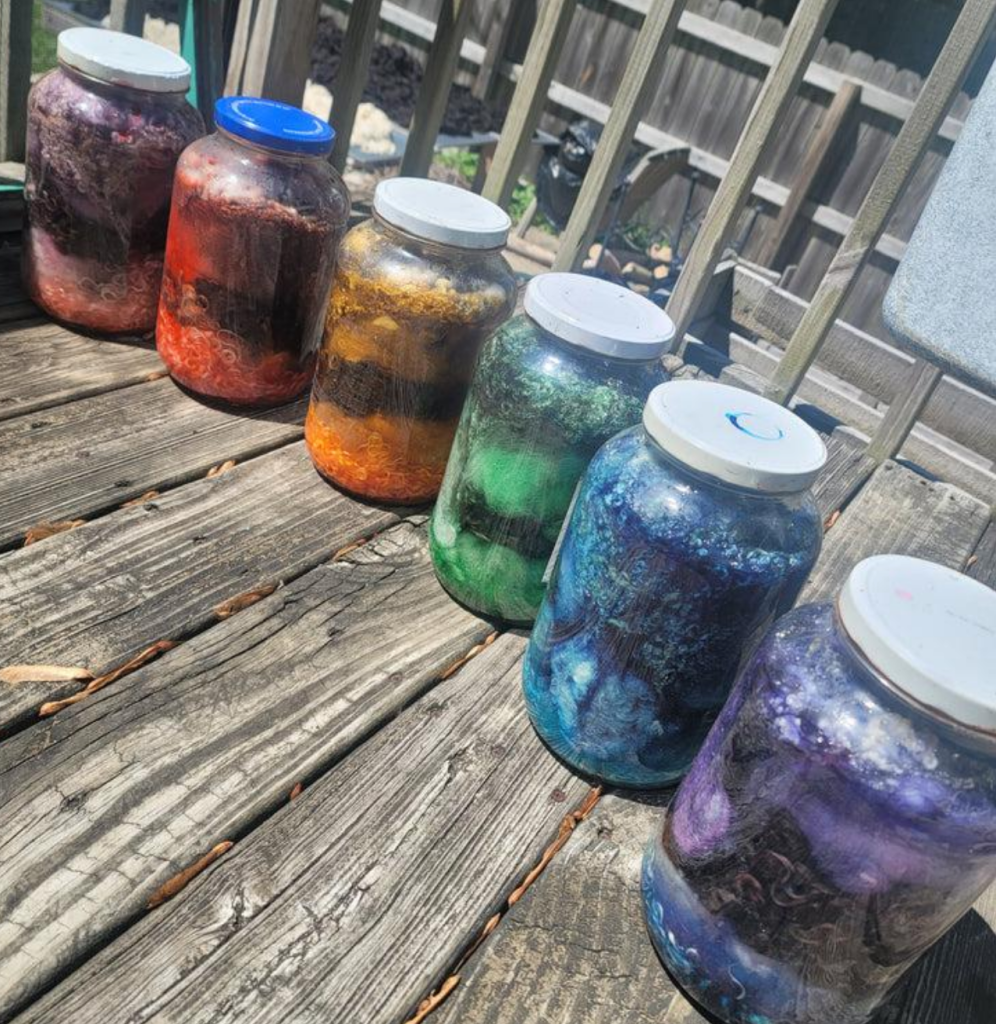 Photo of assorted natural dyes in a large glass  jars on deck.